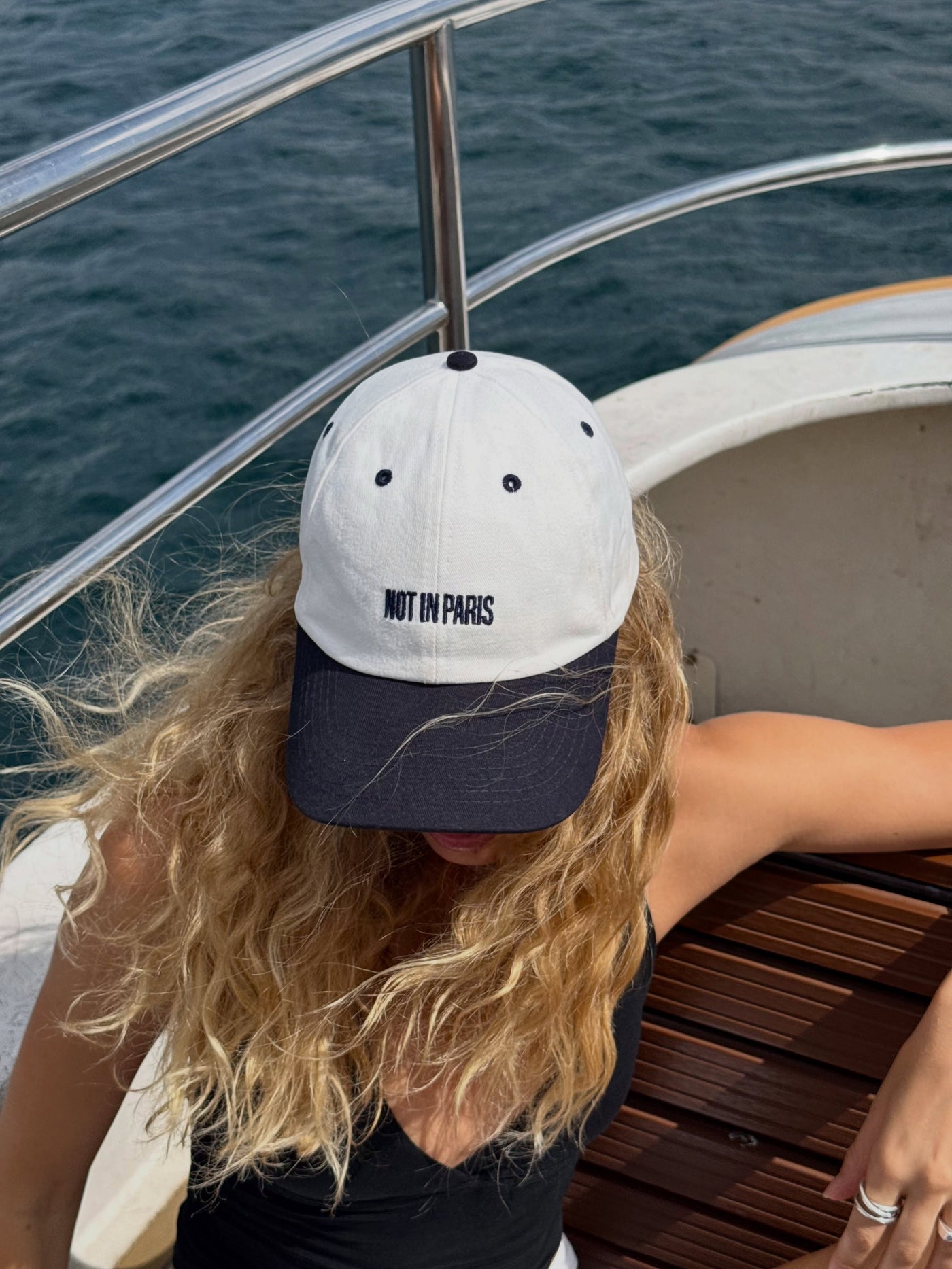 NOT IN PARIS Classic Cap in ecru with navy brim — embroidered logo close-up on the Bosphorus ferry